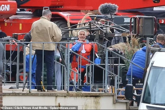 Paul Hollywood in costume behind the railings, with a boom operator alongside