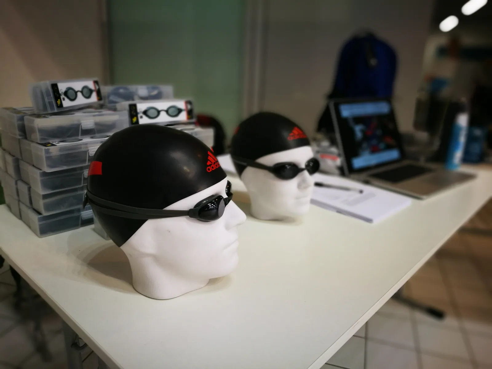 Swim caps and goggles fitted to head forms on a workbench
