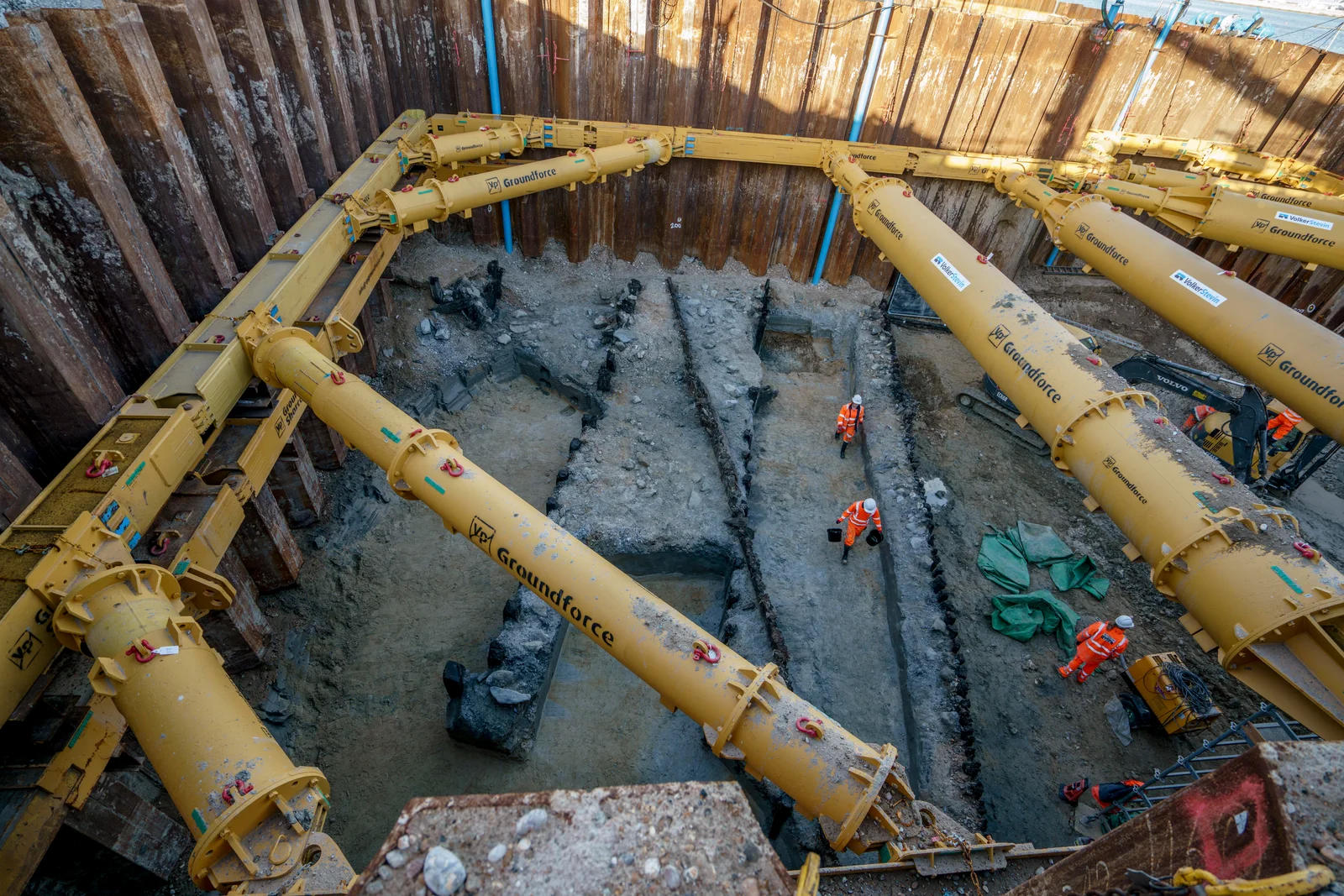 Wide view of the excavation with archaeologists working between the props