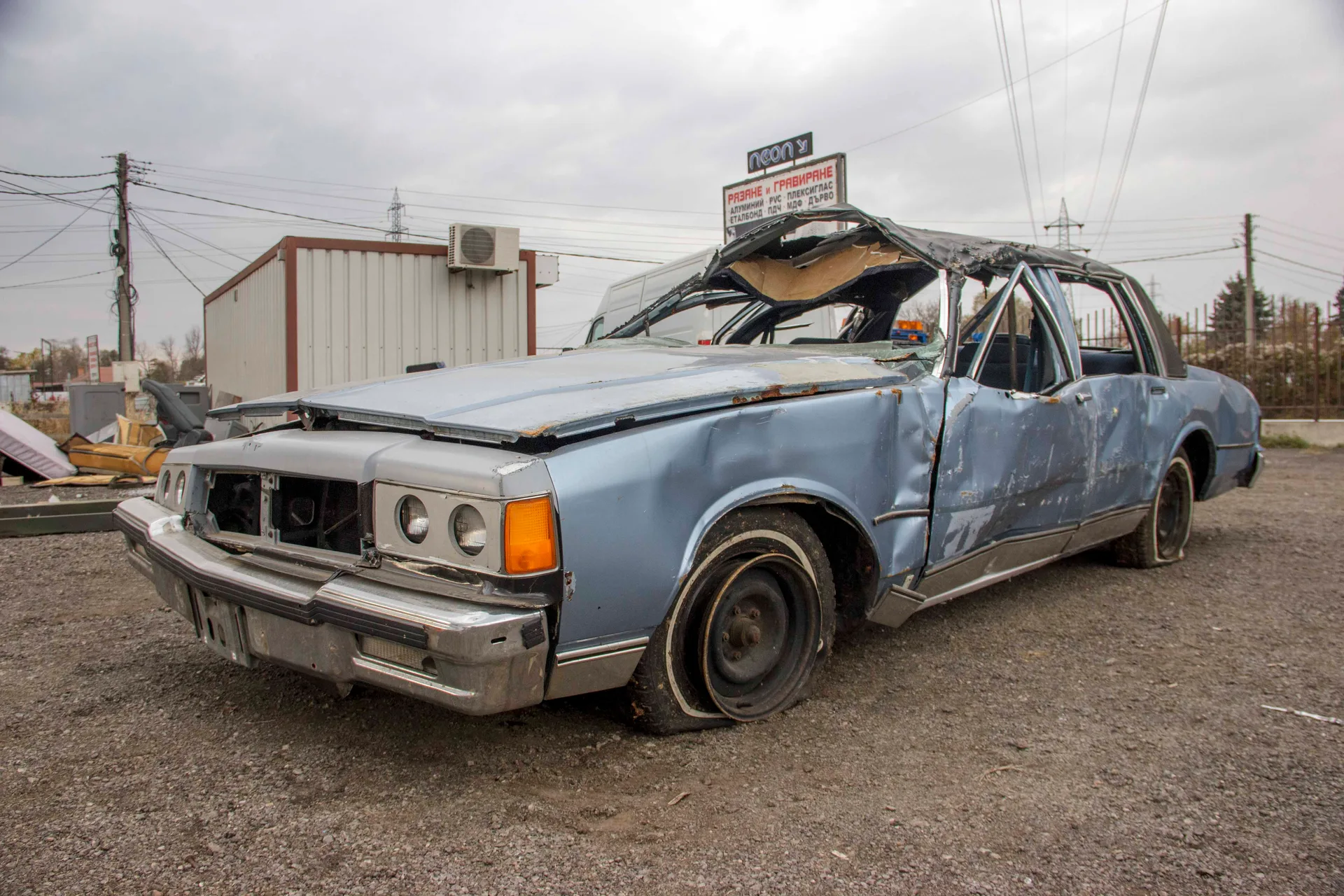Wrecked Chevrolet sedan, front three-quarter view on location