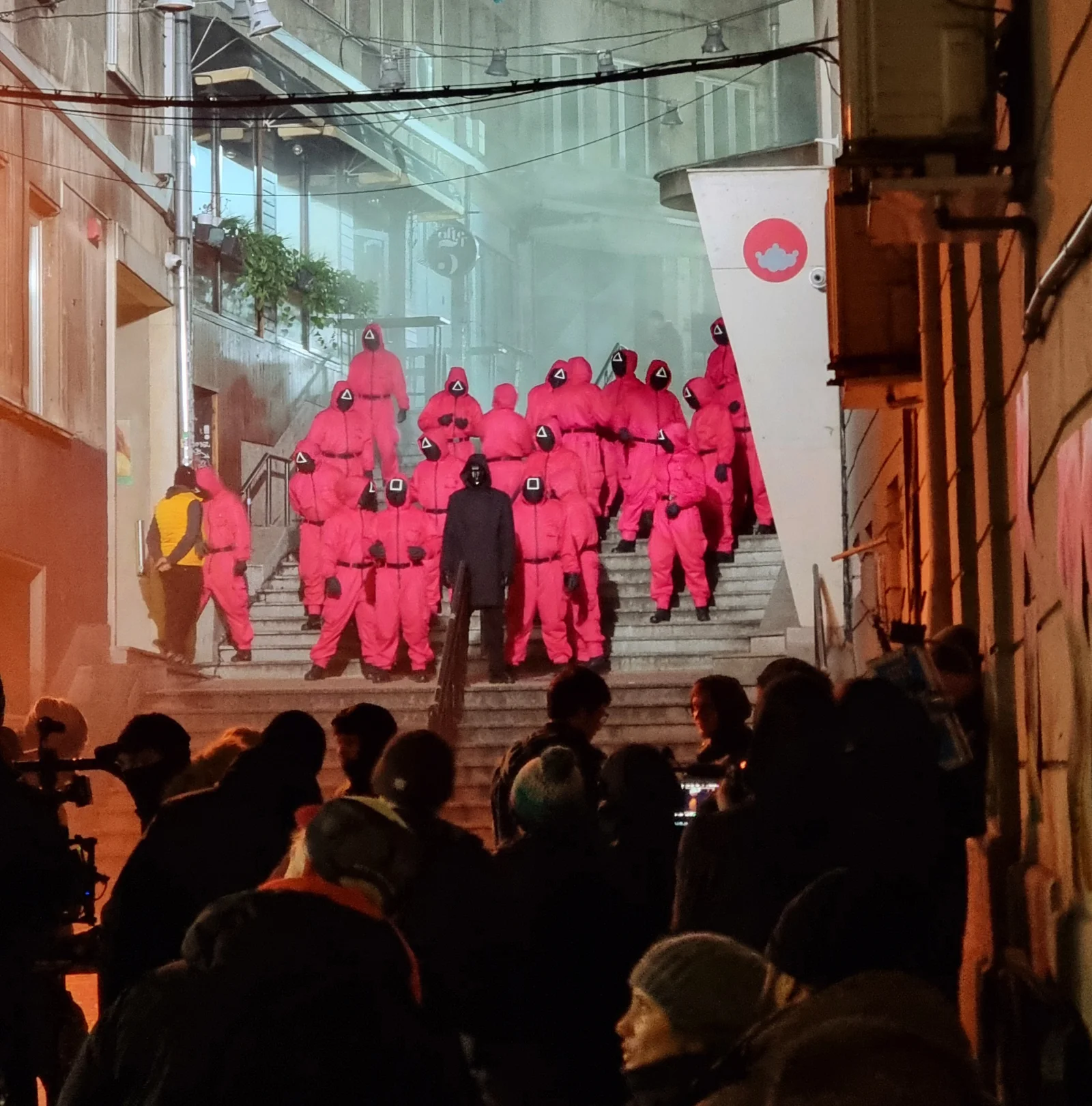 Performers in pink massed on the steps during filming