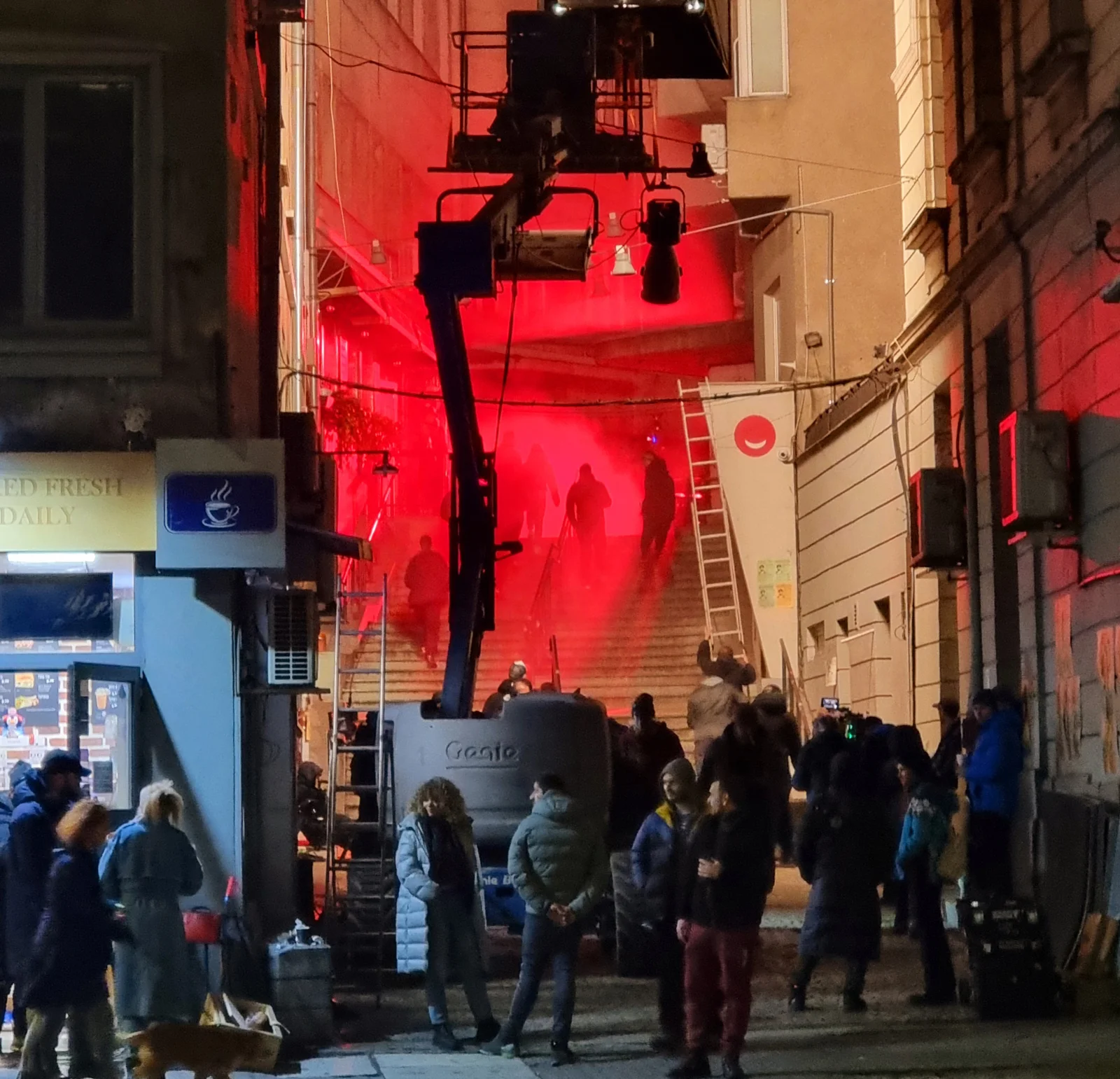 Crew and crowd on set under the red lighting rig