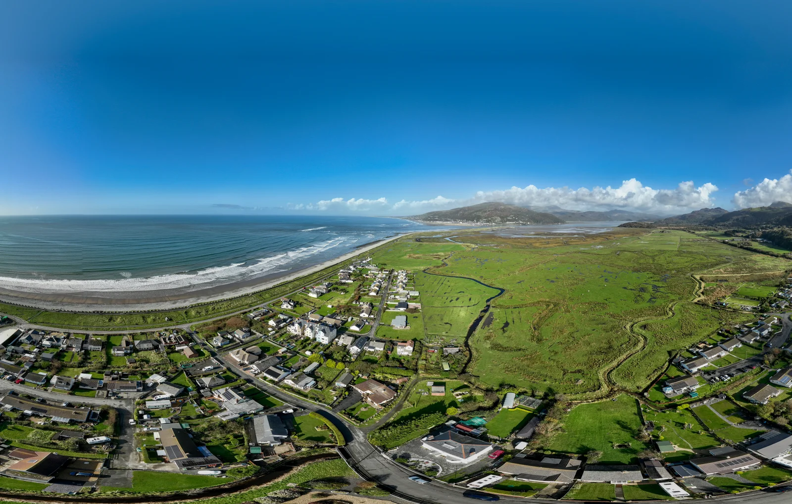 Aerial photograph of Fairbourne village between the Welsh coast and the marshland behind it